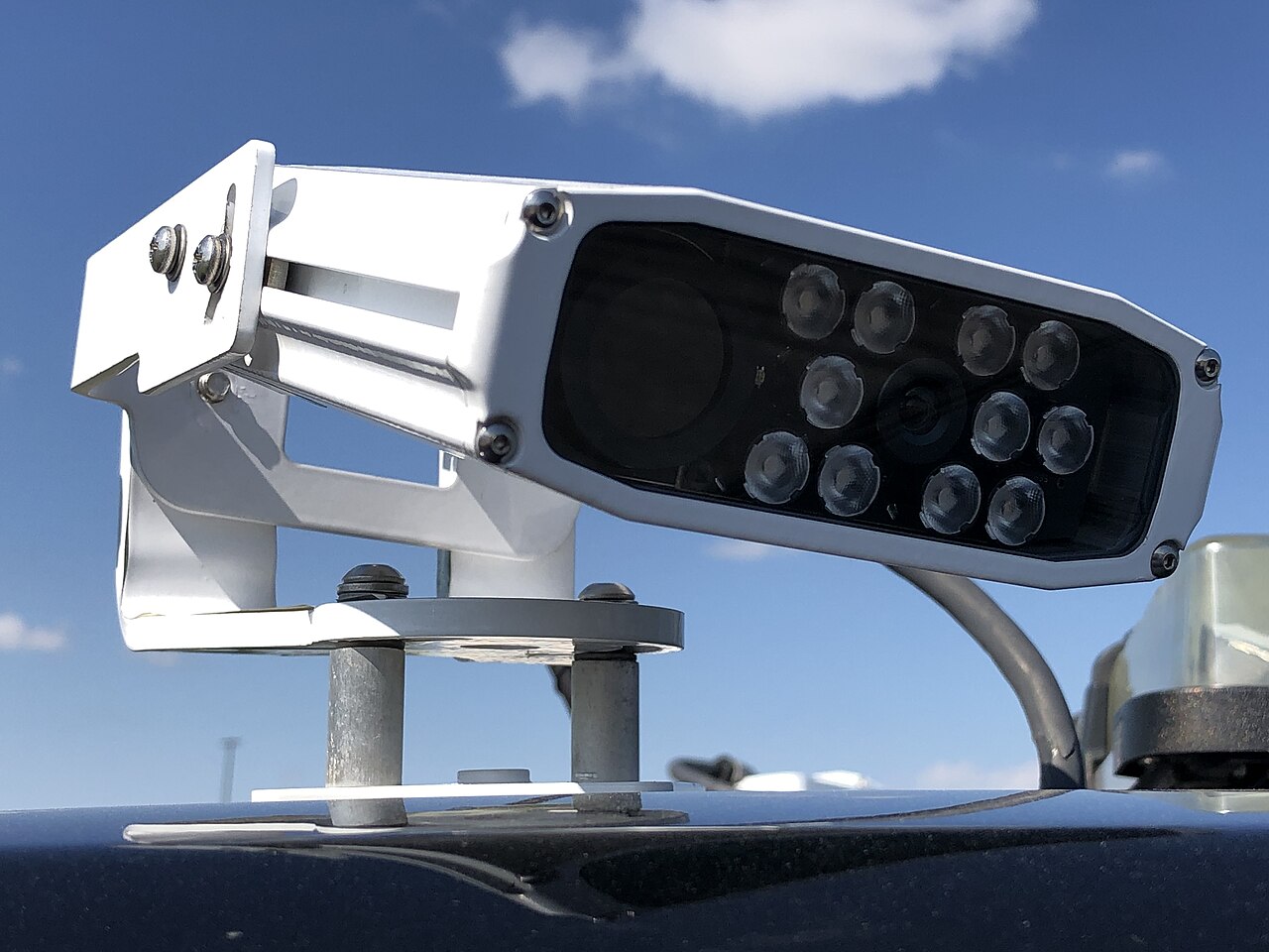 An automatic number plate recognition camera unit mounted on a parking services vehicle, lens pointed at the road